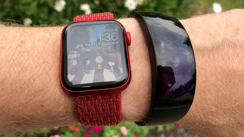 The all-black Amazfit X is shown outside next to an Apple Watch on a wrist with dulled colors in the sun across its curved OLED display.