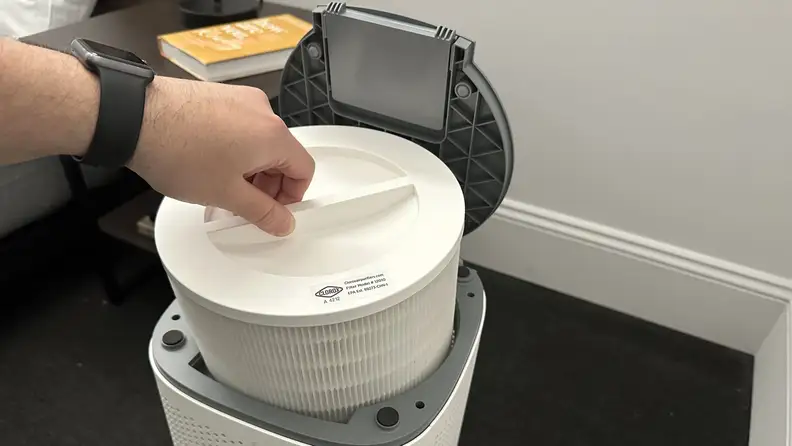 A person's hand pulling out the filter from the air purifier.