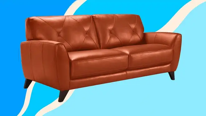 A tan leather couch against a blue background.