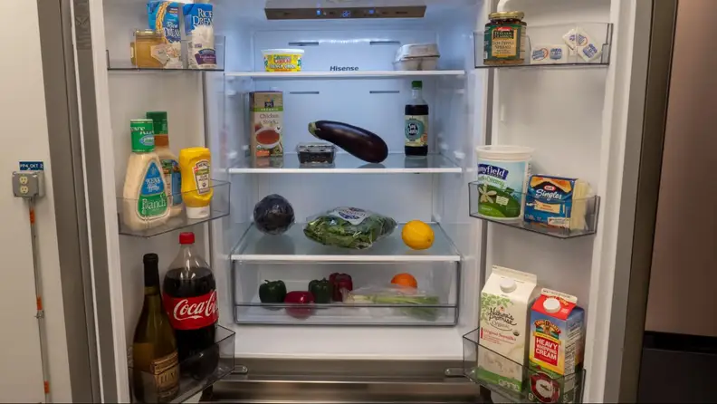 The open fridge showing off all sorts of products, produce and condiments inside.