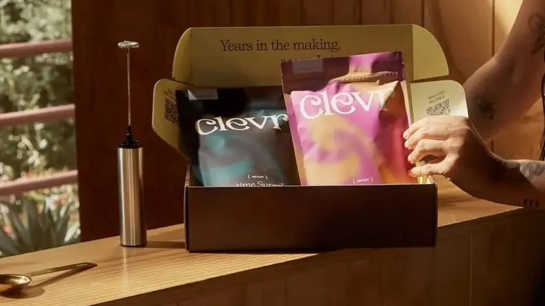 Hand reaching into a box of coffee packets with frother
