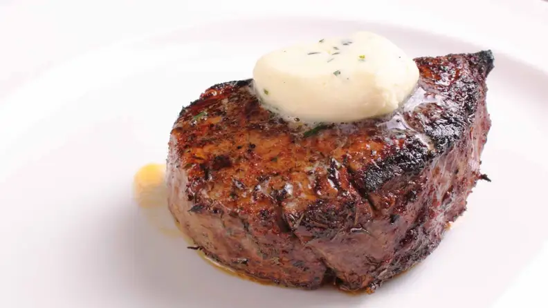 Filet mignon with white steak butter on it, served on a white plate
