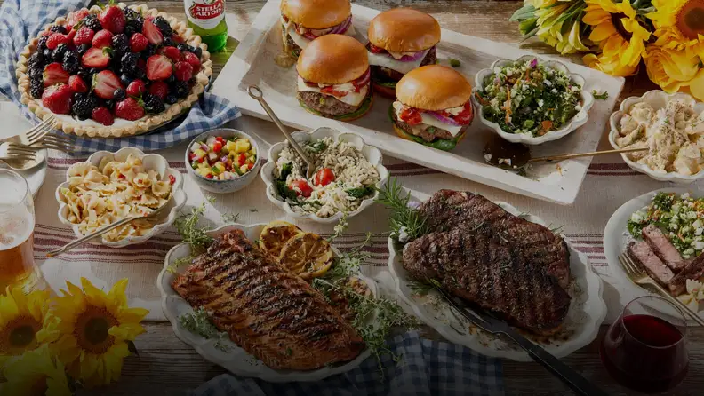 Spread of burgers, steak, salmon, salads, and berry pie