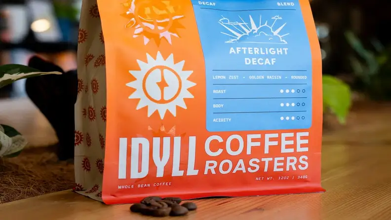 Idyll Coffee Roasters Afterlight Decaf bag with coffee beans on a wood table