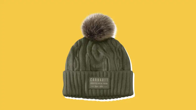 A dark green Carhartt Pom Beanie on a yellow background.