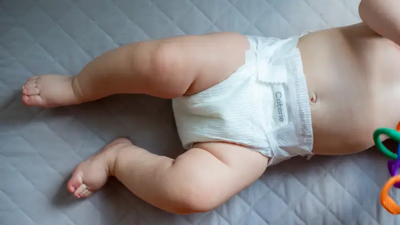 Belly, diaper, and legs of baby laying down wearing Coterie The Diaper.