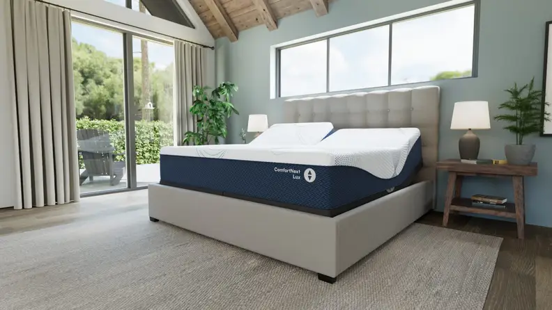 ComfortNext™ Lux mattress on a grey rug in a bedroom with a sliding glass door.