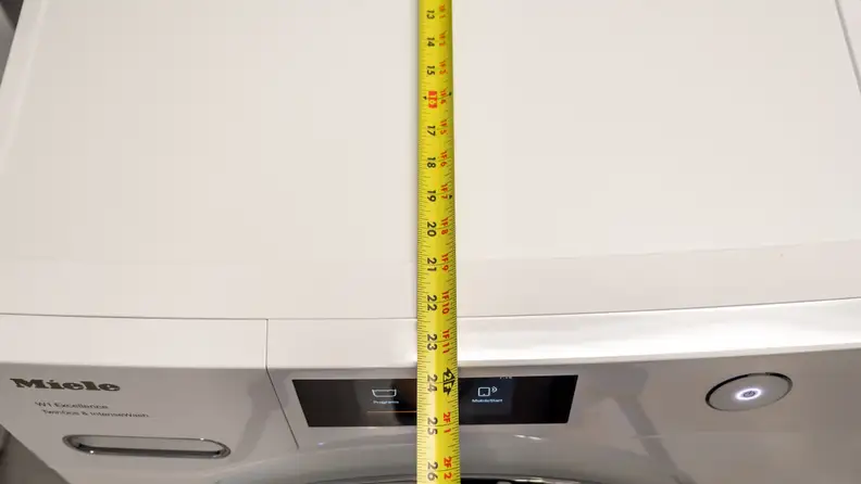 A measuring tape extends across the top of the washer, showing it's less than 24 inches deep.