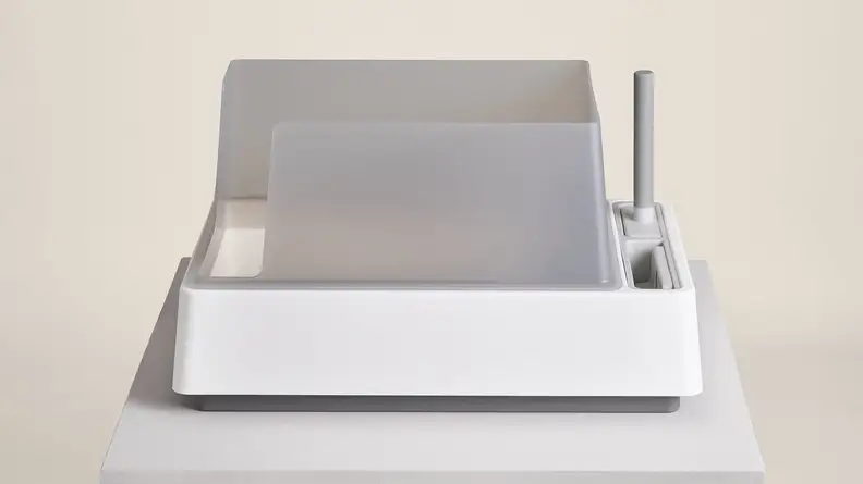 The Tuft + Paw litter box features high walls on three sides and slots for cleaning tools to the right.
