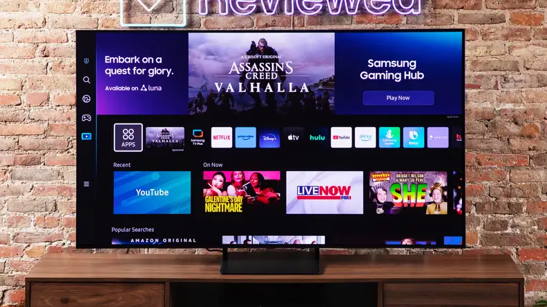 The Samsung S90C QD-OLED TV on an entertainment center with a brick background.