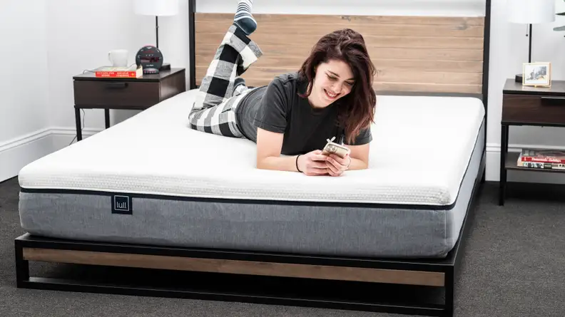 A person on their phone lying on a Lull Original mattress