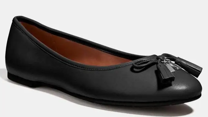 A black leather Coach shoe, waiting to be worn.
