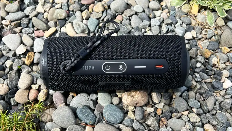 A black, cylindrical Bluetooth speaker is shown from the backside with a USB-C charging input.