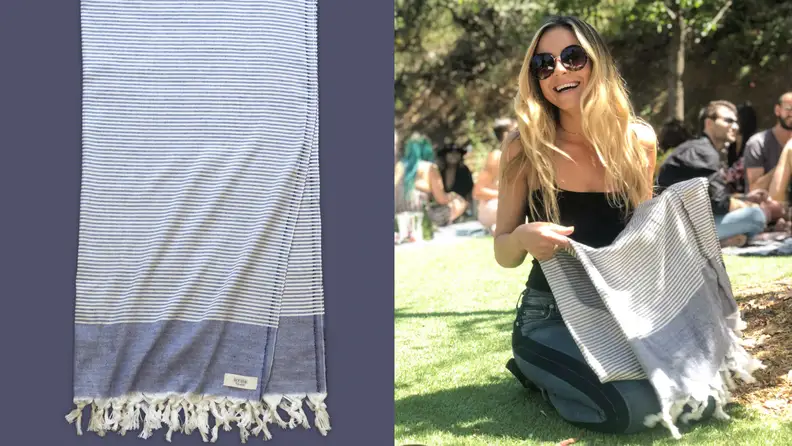 Woman sitting in the grass holding a blue Teema towel.
