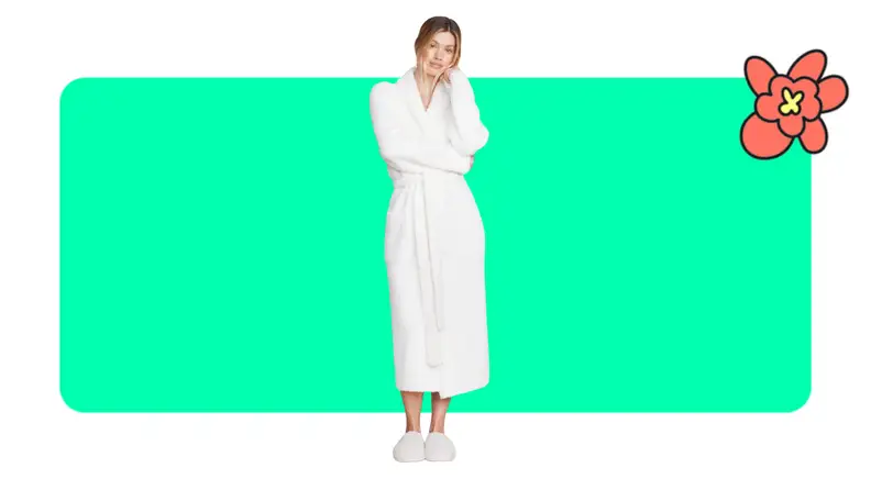 Model showcasing a white Barefoot Dreams robe and slippers with head resting on their hand.