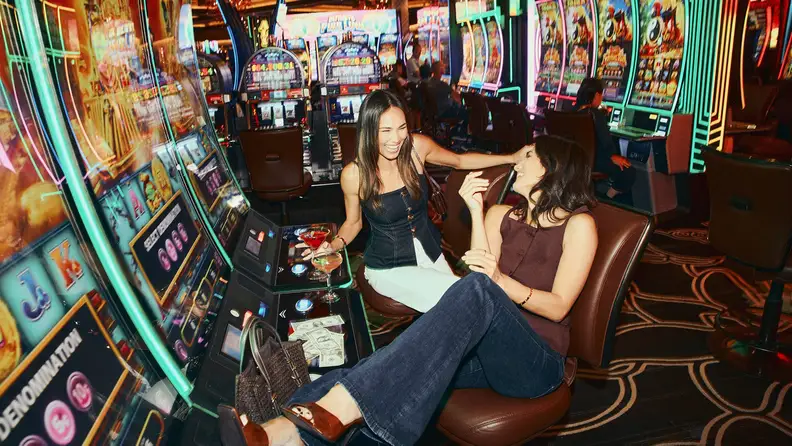 Two ladies with cocktails lounging by the slot machines