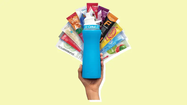 A hand holding a bottle of Cirkul with plenty of hydration packets.