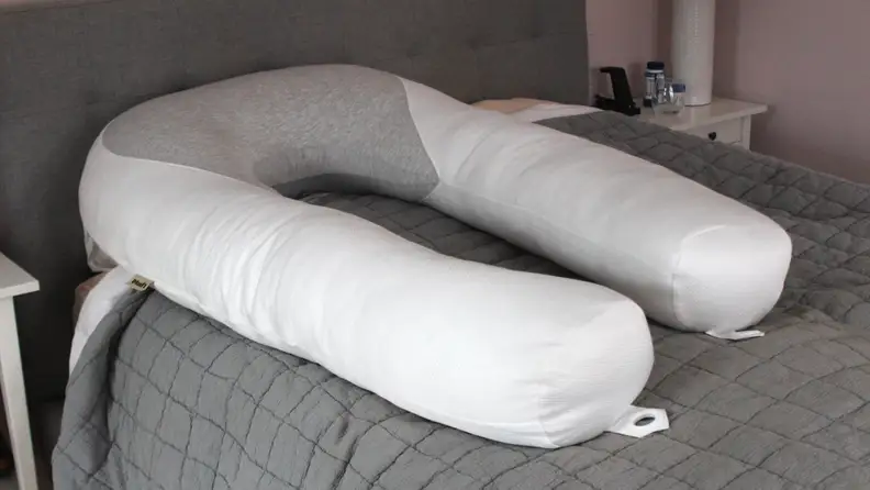 The Hugl Body pillow with a white cover, resting on top of a bed.