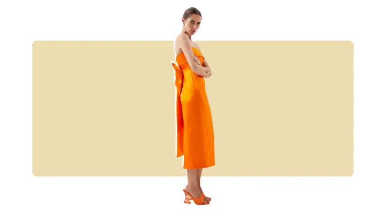 A columnar orange satin midi dress with a foldover neckline and a bow on the back.