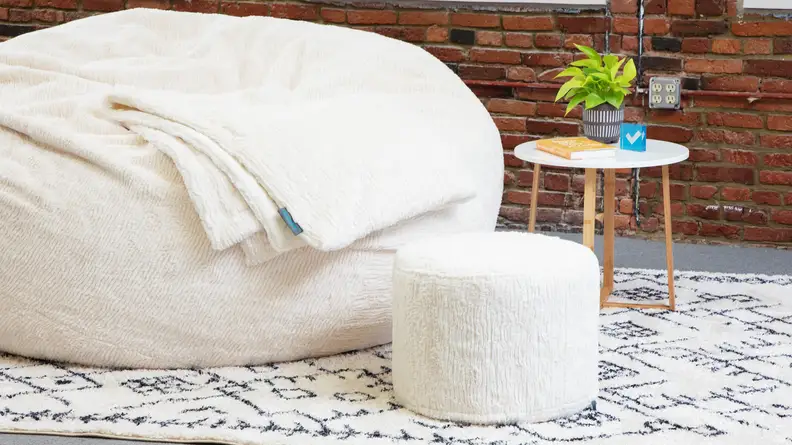 A squattoman sitting next to one of Lovesac’s Sacs.