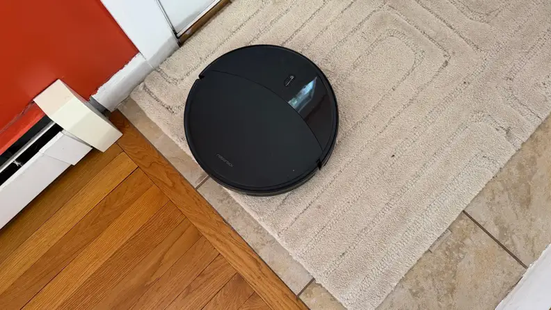 A black robot vacuum tackles various floor types and heights