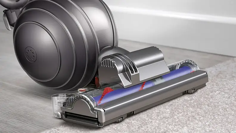 A Dyson vacuum cleans a carpet.