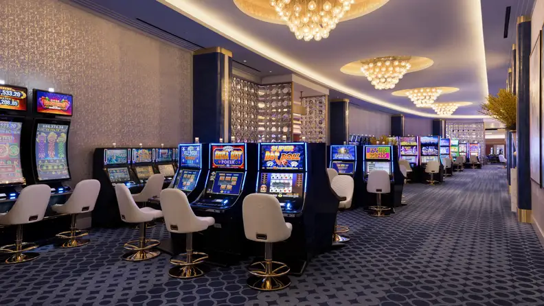 Elegant Fontainebleau Las Vegas casino featuring rows of slot machines, white gaming chairs, crystal chandeliers, and a modern luxury design.