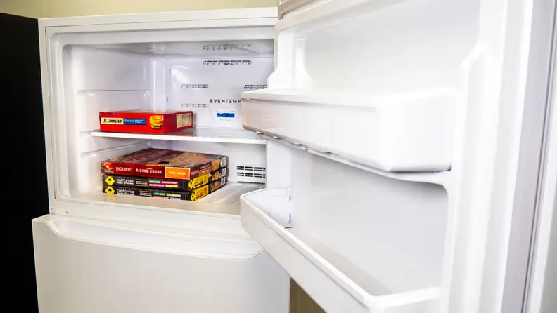 A shot of the Frigidaire FFTR1814VW top-freezer refrigerator's freezer door and interior. The interior has some frozen pizza boxes stacked up inside, for scale.