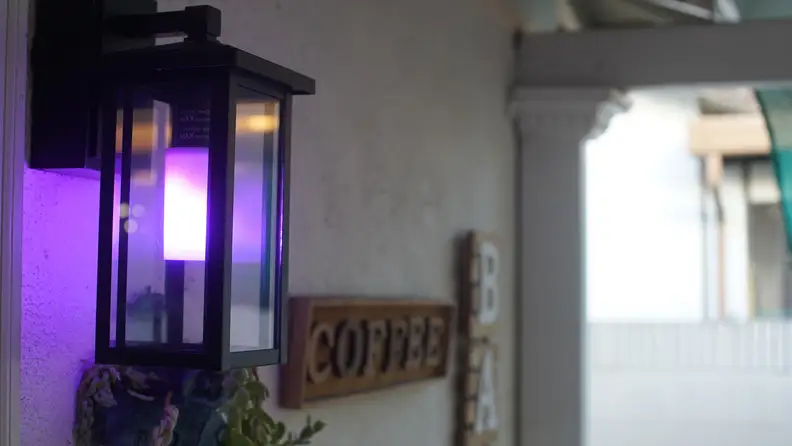 Linkind T19 Smart Flame Bulb illuminated in purple on a white exterior wall.