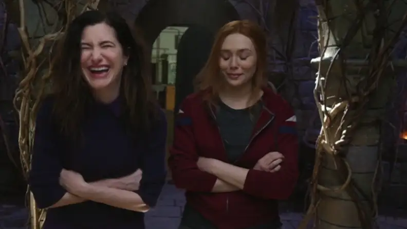 A still from the Assembled series featuring Kathryn Hahn and Elizabeth Olsen in costume, breaking character by laughing.