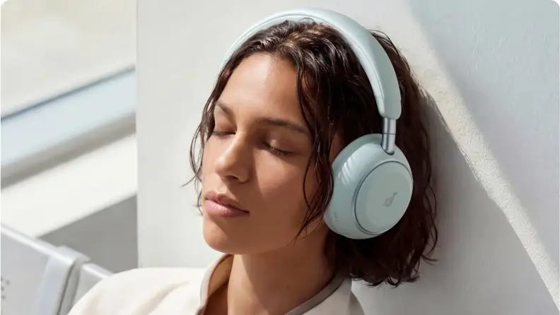 Woman listening to light blue Soundcore over-ear headphones.