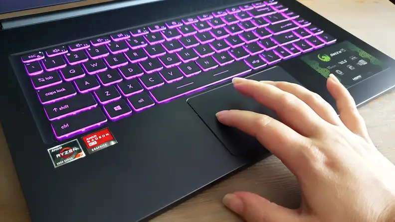 A hand touching a laptop's trackpad