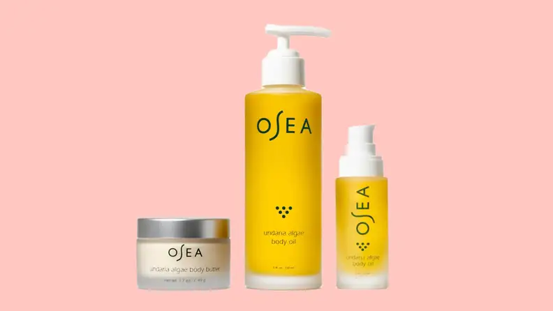 Three skincare products stand against a pink background.