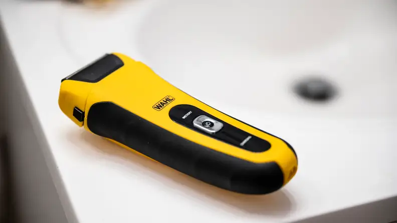 An image of a Wahl Lifeproof electric shaver sites on the lip of a white porcelain bathroom sink.