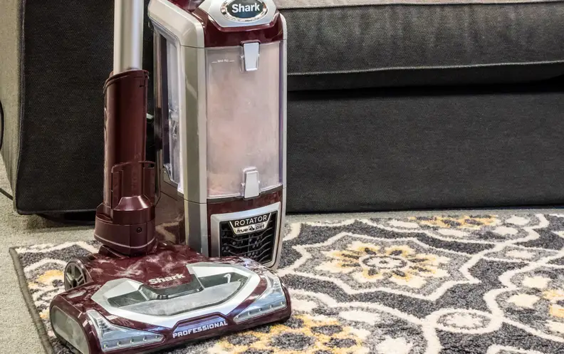 The Shark NV752 TruePet standing on a patterned rug with a couch in the background.