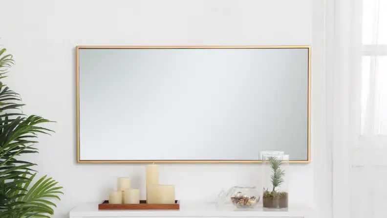 Wide gold-framed mirror with candles and a plant