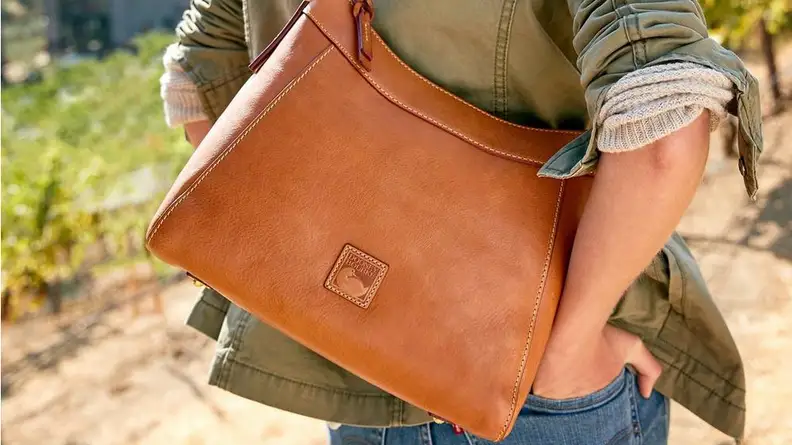 Woman carrying large Dooney & Bourke satchel.