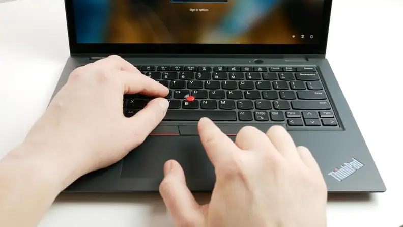 Person resting hands and fingers on the keyboard and trackpad of the Lenovo ThinkPad L13 Yoga Gen 4 laptop.