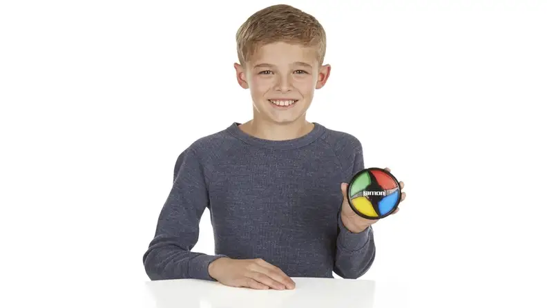 A boy holding a small Simon toy
