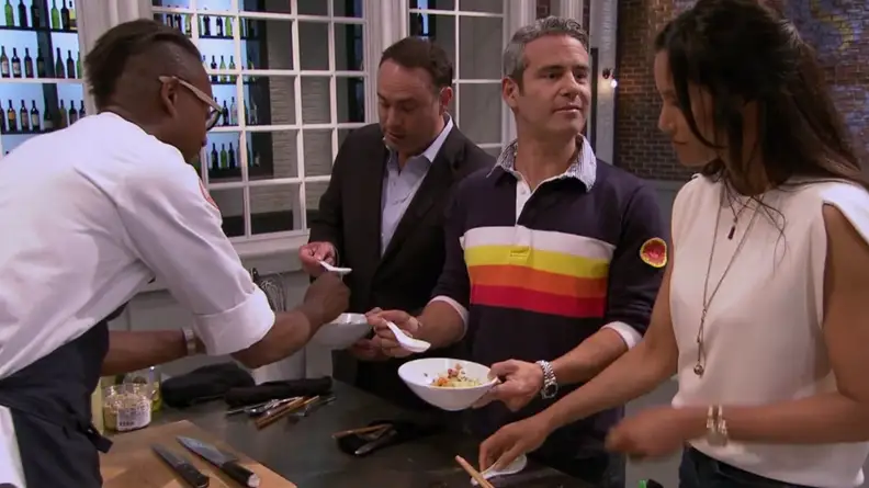 A still from Top Chef featuring Padma and Andy Cohen sampling one of the contestant's dish.