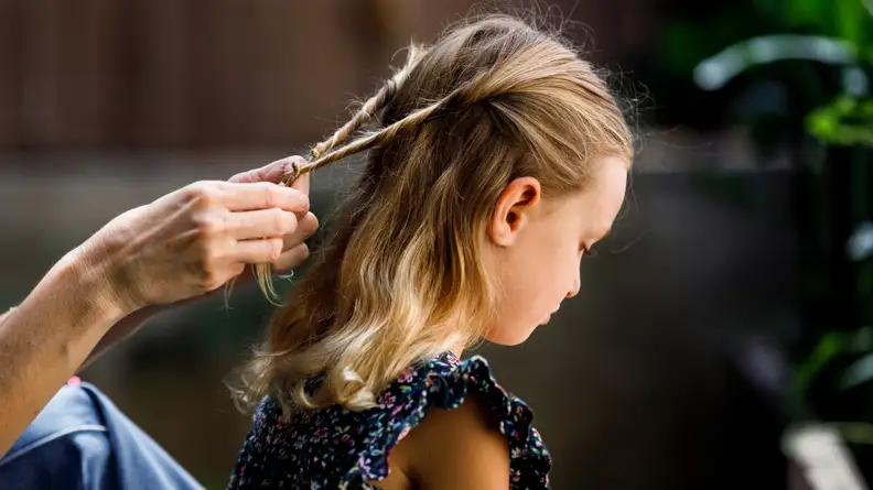 A young girl getting her hair twisted