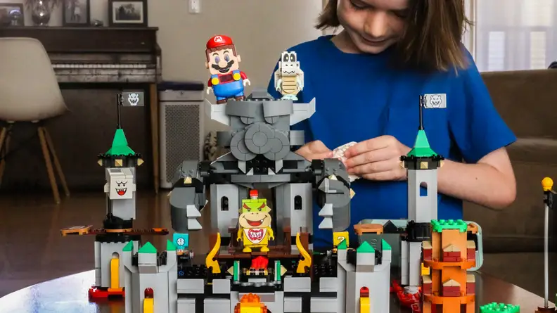 A setup of the Bowser's Castle Boss Battle expansion set, with a child building in the background.
