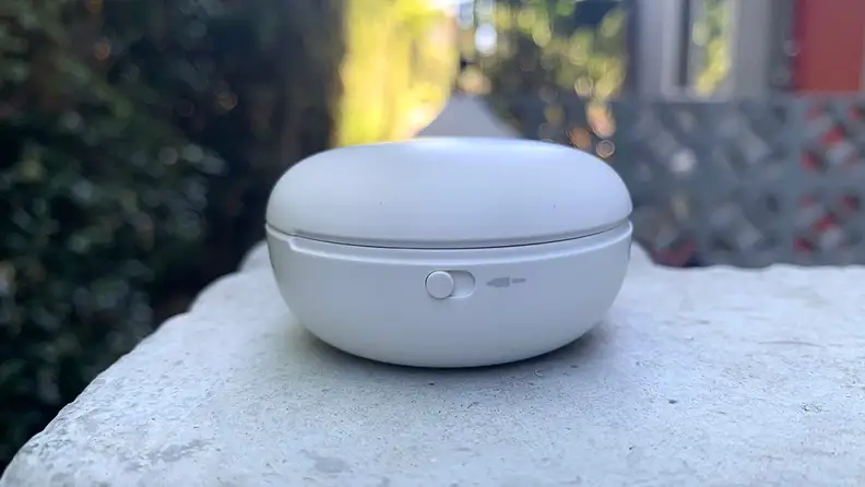 A view of the side of the T90Q earbuds case, sitting on a stone wall.