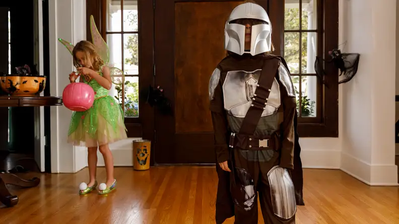 A child dressed as the Mandalorian standing in an entryway.