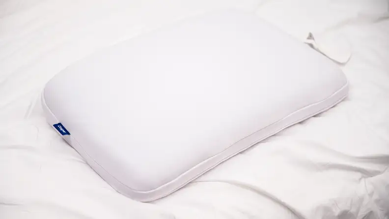 Memory foam pillow laying on white mattress.