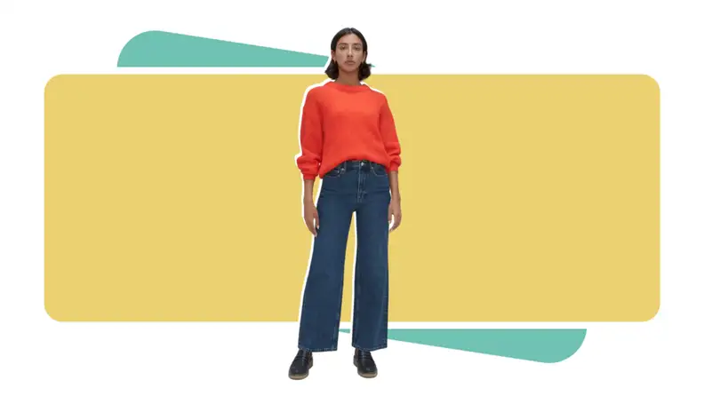Woman wearing Everlane flare jeans and orange sweater.