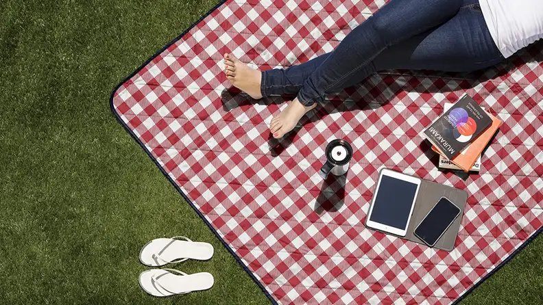 A person lays on a picnic blanket in the grass.