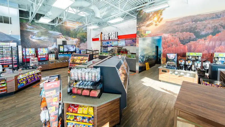 Interior of a Maverik store with scenic mountain murals and a food counter