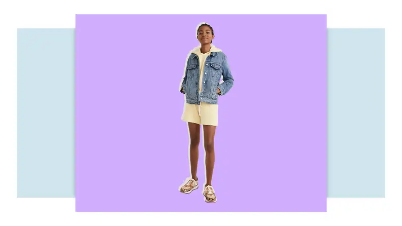 Model wearing denim jean jacket over dress.