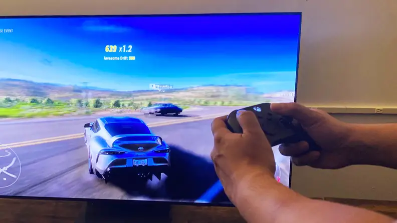 A close-up of someone's hands holding an Xbox Series X controller as they play Forza Horizon 5 via the Samsung Gaming Hub
